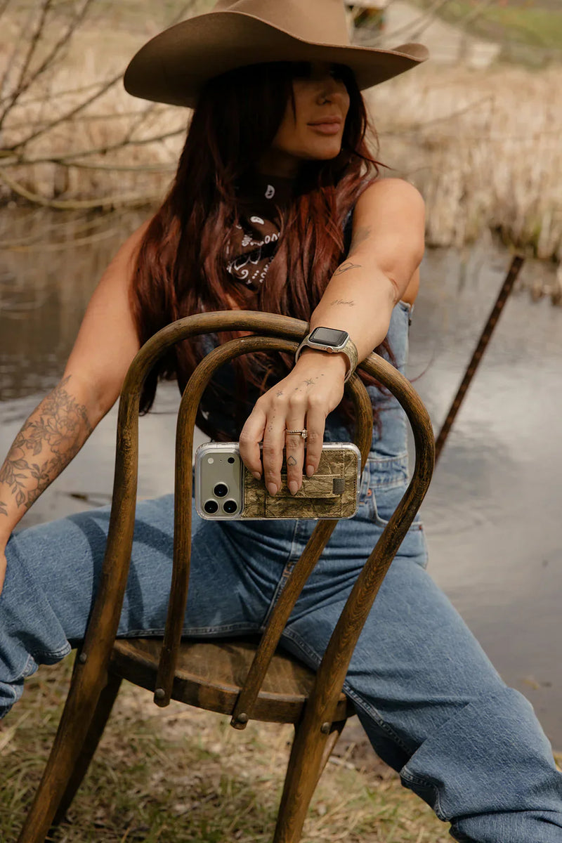 A woman sitting on a chair holding a leather Walli Case.