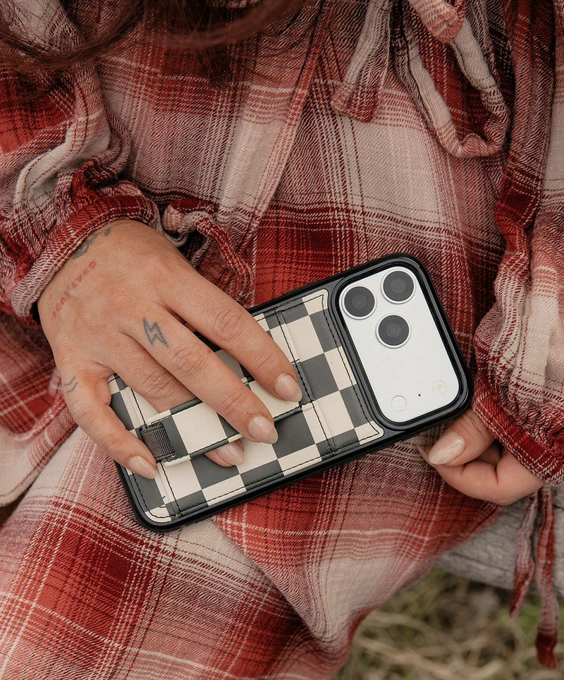 A woman holding her phone secured by a leather Walli Case 